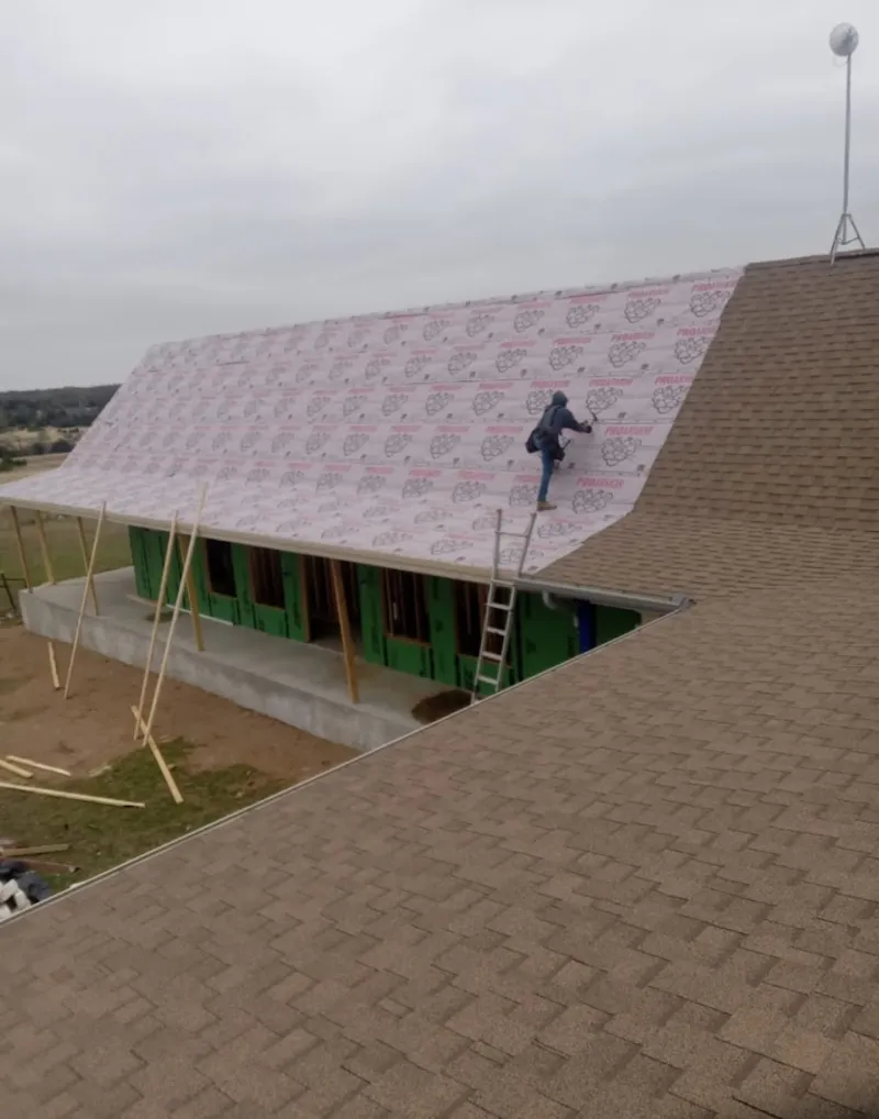 Worker preparing underlayment for a metal roof installation in Ann Arbor